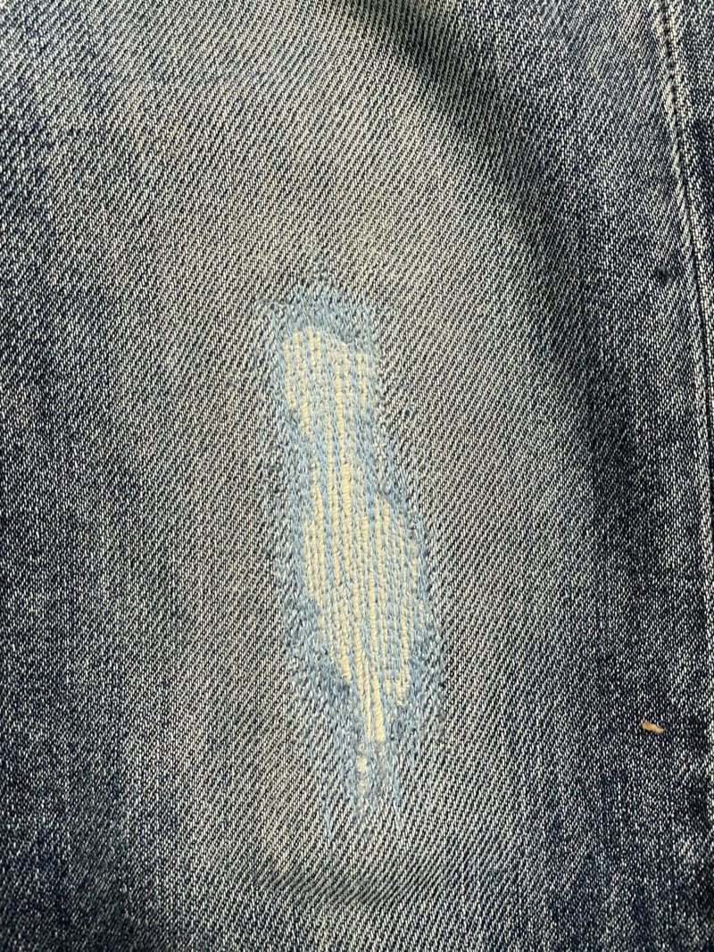 Machine reweave repairing a blown-out worn spot on indigo denim jeans