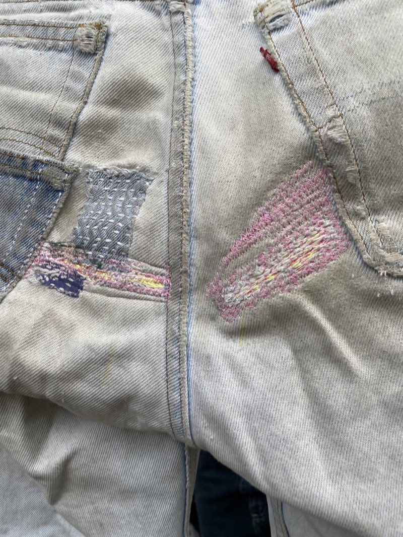 Colorful visible mending and sashiko-style darning on light-wash denim
